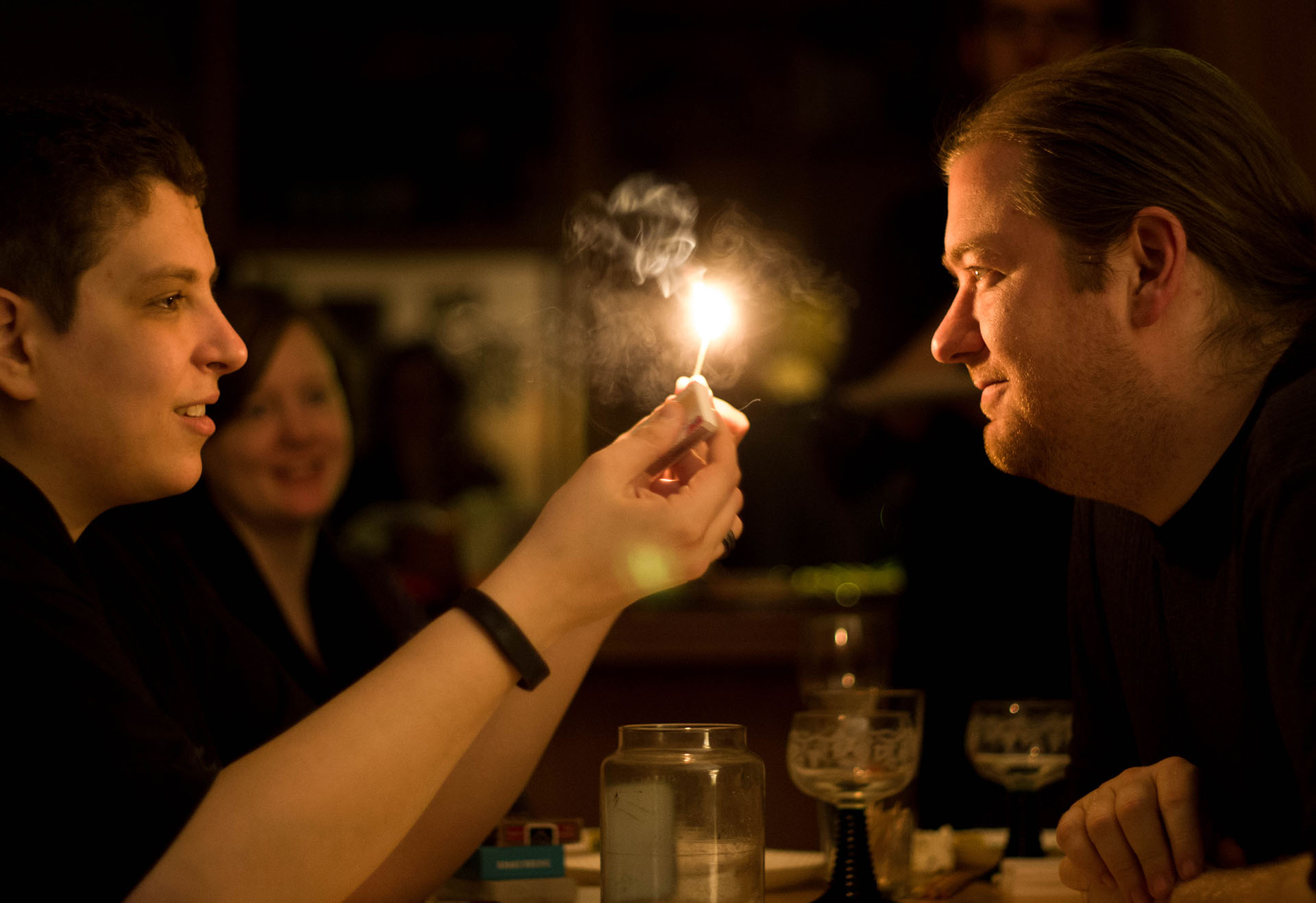 Two people stare at a smoking flame held between them